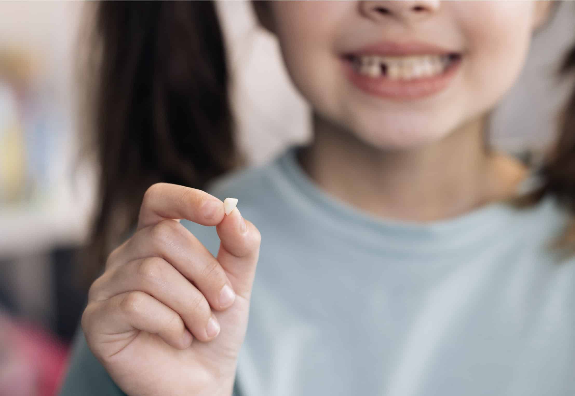young girl holding tooth